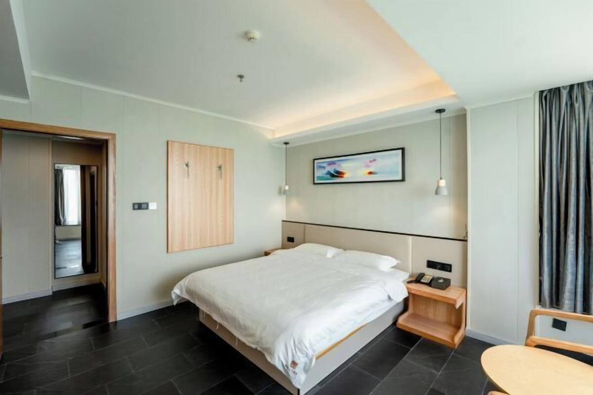 Une chambre d’hôtel moderne, dotée d’un grand lit, de tables de chevet, d’un bureau et d’une chaise.