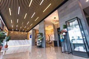 Un vestíbulo moderno con un mostrador de recepción de mármol, iluminación vertical y una vitrina de cristal.