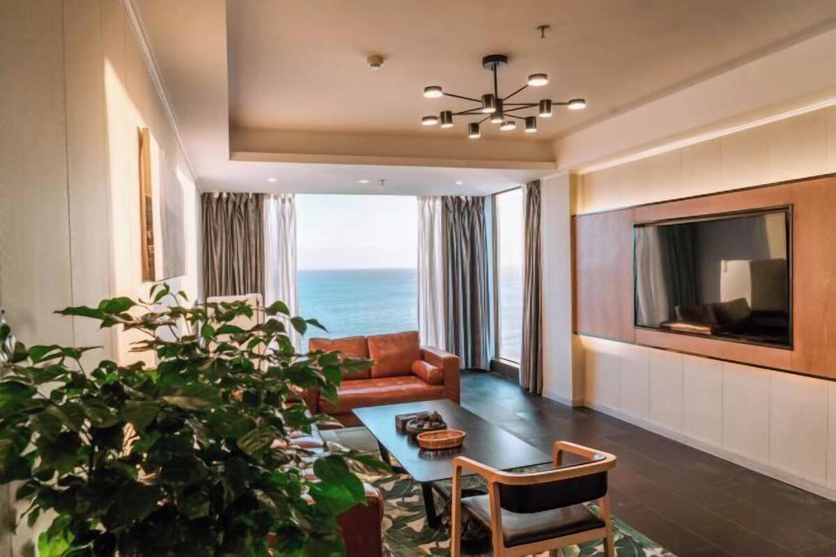 Un salon moderne doté d’un grand téléviseur, d’un canapé, d’une table basse et offrant une vue sur la mer.
