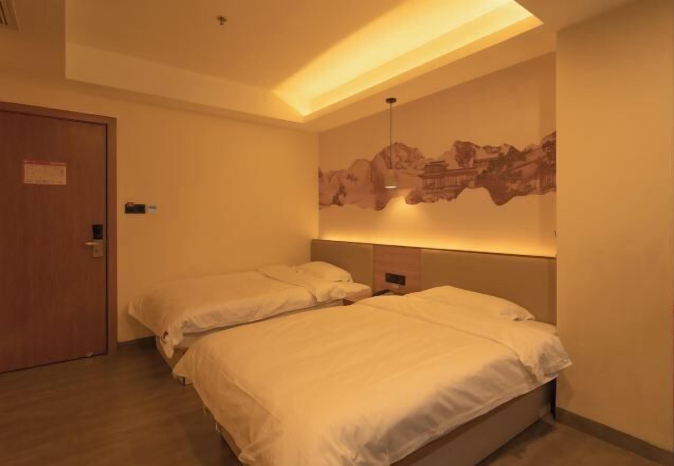 A hotel room with two beds, a wooden door, and a wall-mounted artwork.