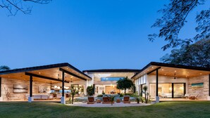 Una casa moderna con un porche cubierto, piscina y zona de comedor.