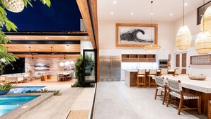 Una cocina moderna con una isla grande, electrodomésticos de acero inoxidable e iluminación colgante.