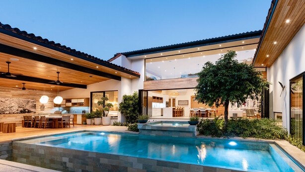 Una casa moderna con piscina, techo de madera y ventanas amplias.