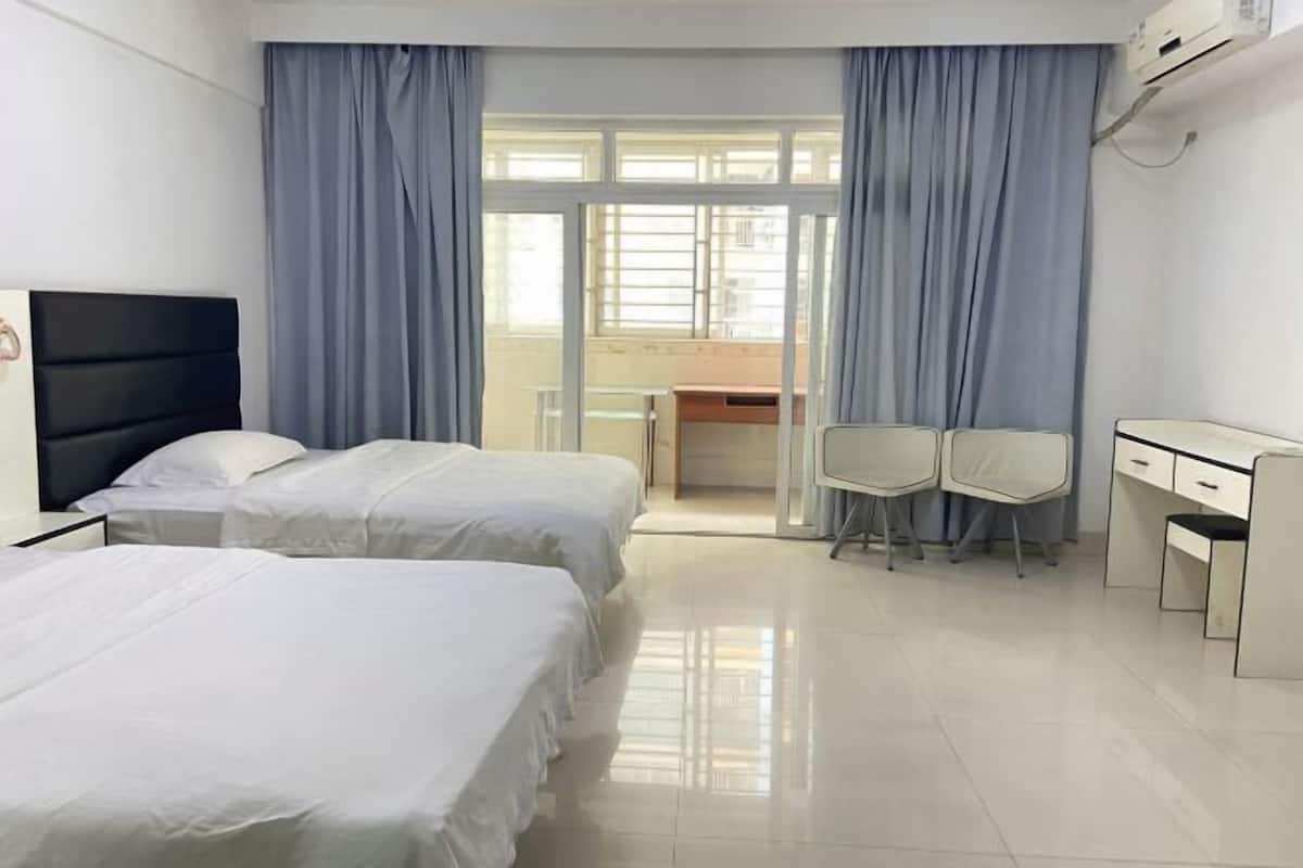 Une chambre d’hôtel avec deux lits, un bureau, deux chaises et une fenêtre avec des rideaux.