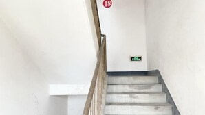 A staircase with a wooden handrail and a green emergency exit sign on the wall.