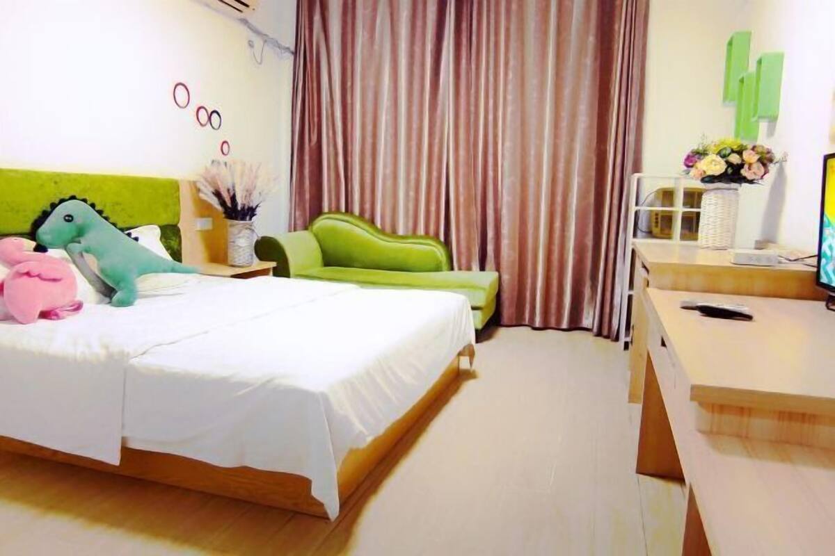 Une chambre d’hôtel avec un lit, un bureau, une chaise et une fenêtre avec des rideaux.