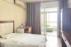A hotel room with a bed, a desk, and a balcony with a view.