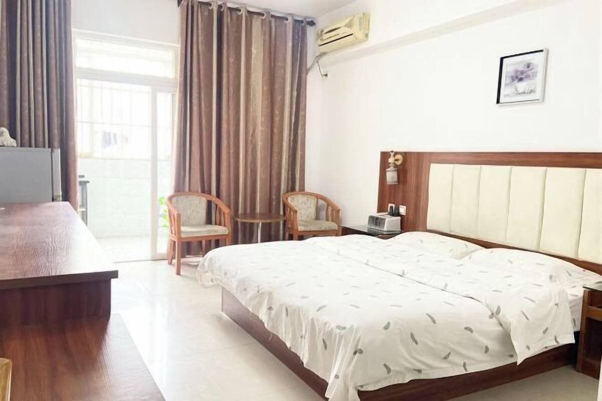 Une chambre d’hôtel avec un lit, un bureau, une chaise, une petite table et un tableau au mur.