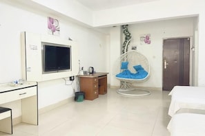 A hotel room with a bed, a desk, a chair, and a television.
