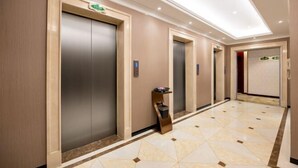 A hotel corridor with three elevators, a marble-tiled floor, and a modern design. - Vienna Hotel (Zaozhuang Xuecheng Distrct High-speed Railway Station) (Zaozhuang)