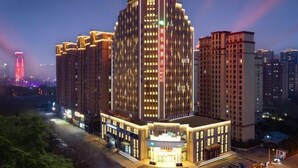 A multi-story hotel building with illuminated signage and a well-lit entrance. - Vienna Hotel (Zaozhuang Xuecheng Distrct High-speed Railway Station) (Zaozhuang)