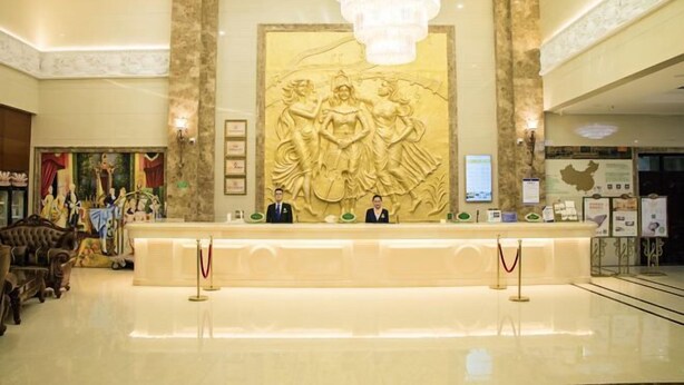 A lobby with a reception desk, a chandelier, and a large wall sculpture. - Vienna Hotel (Zaozhuang Xuecheng Distrct High-speed Railway Station) (Zaozhuang)