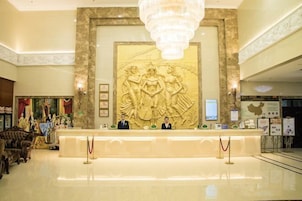 A lobby with a reception desk, a chandelier, and a large wall sculpture.