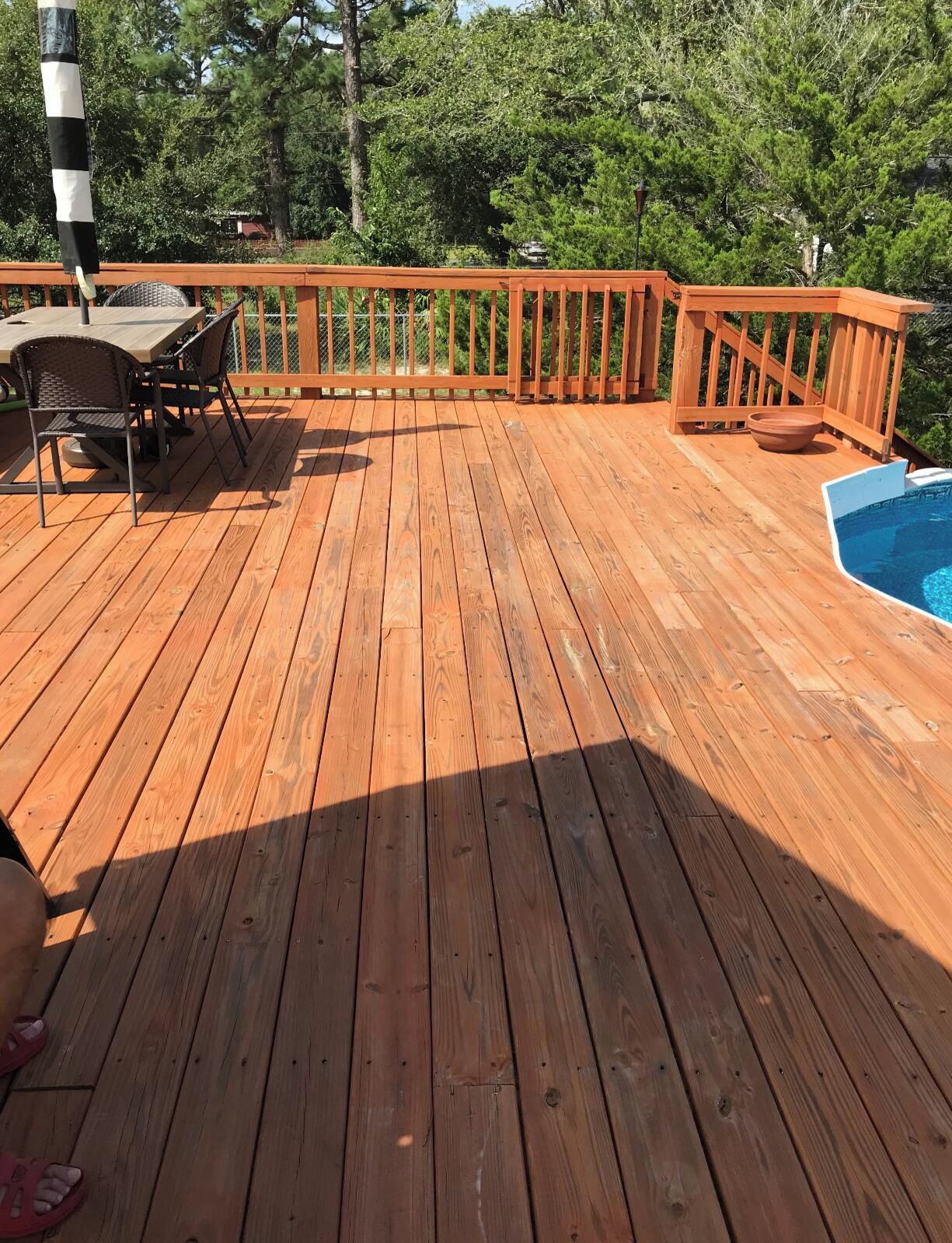 A wooden deck with a pool, surrounded by trees.