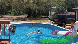 A swimming pool with inflatable toys, a wooden deck, and a vehicle in the background. - Bam!!! August Special rate 79 guests love this little paradise!  Private pool! (Gulf Breeze)