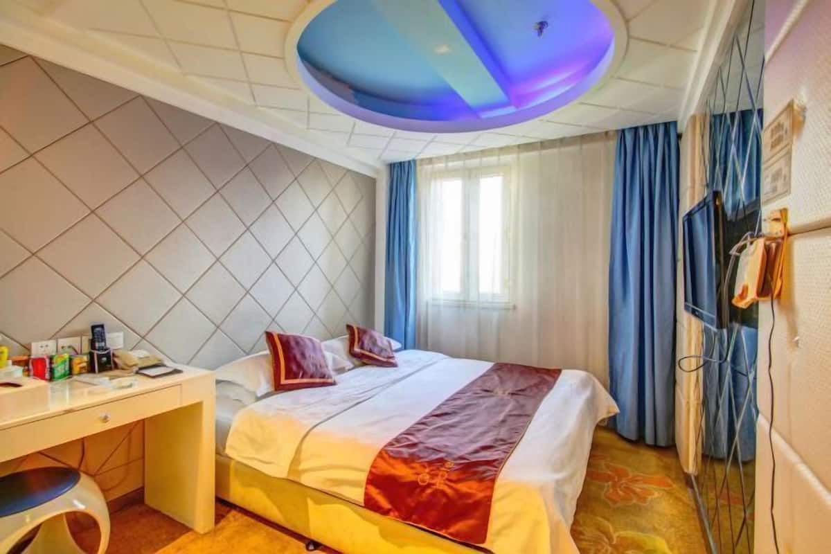 A hotel room with a bed, a desk, and a TV.