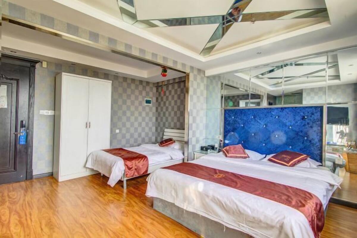 Una habitación de hotel moderna con dos camas, un espejo grande y suelo de madera.
