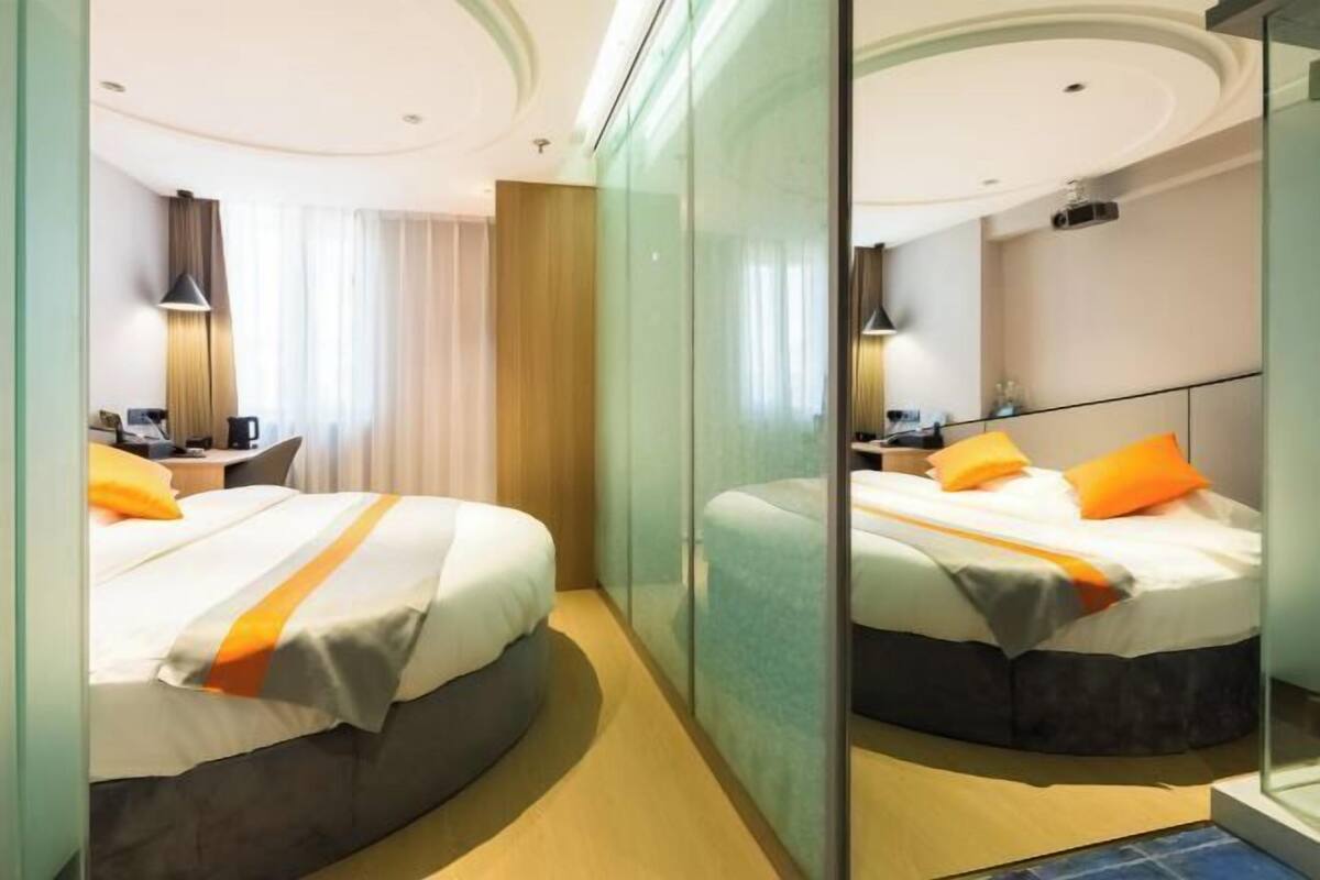 Una habitación de hotel con cama, escritorio, silla, lámpara y ventana.