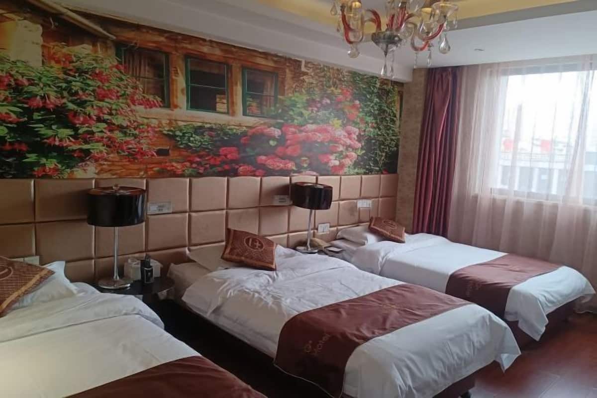 A hotel room with two beds, a large floral mural on the wall, a chandelier, and a window with curtains.