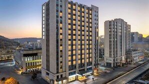 Un hotel de varios pisos con un llamativo letrero de Days Inn, que presenta un diseño arquitectónico moderno con una fachada plana y patrones uniformes en las ventanas.