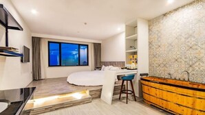 Habitación de hotel moderna con una cama grande, un escritorio, un tocador de madera y una pared con estampado.