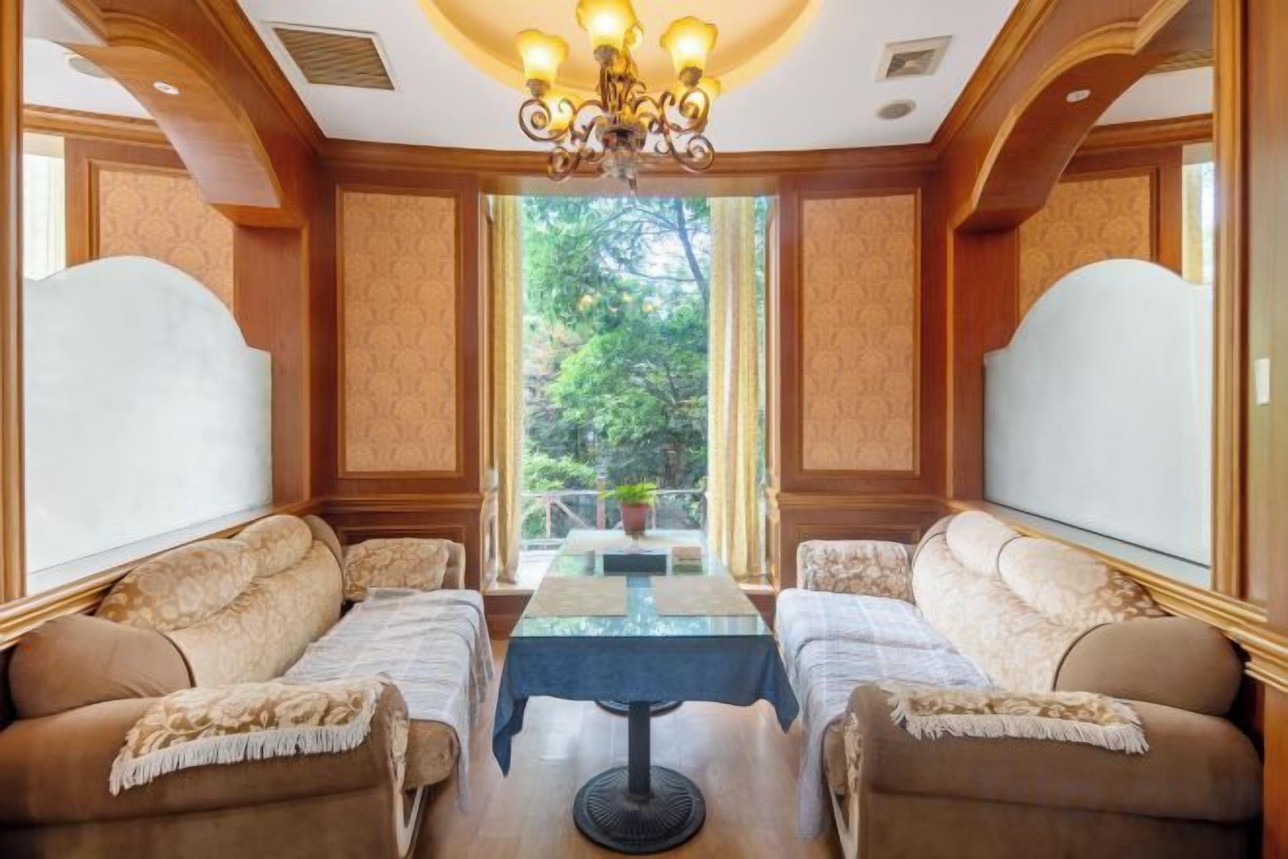 A room with a dining table, two sofas, and a chandelier.