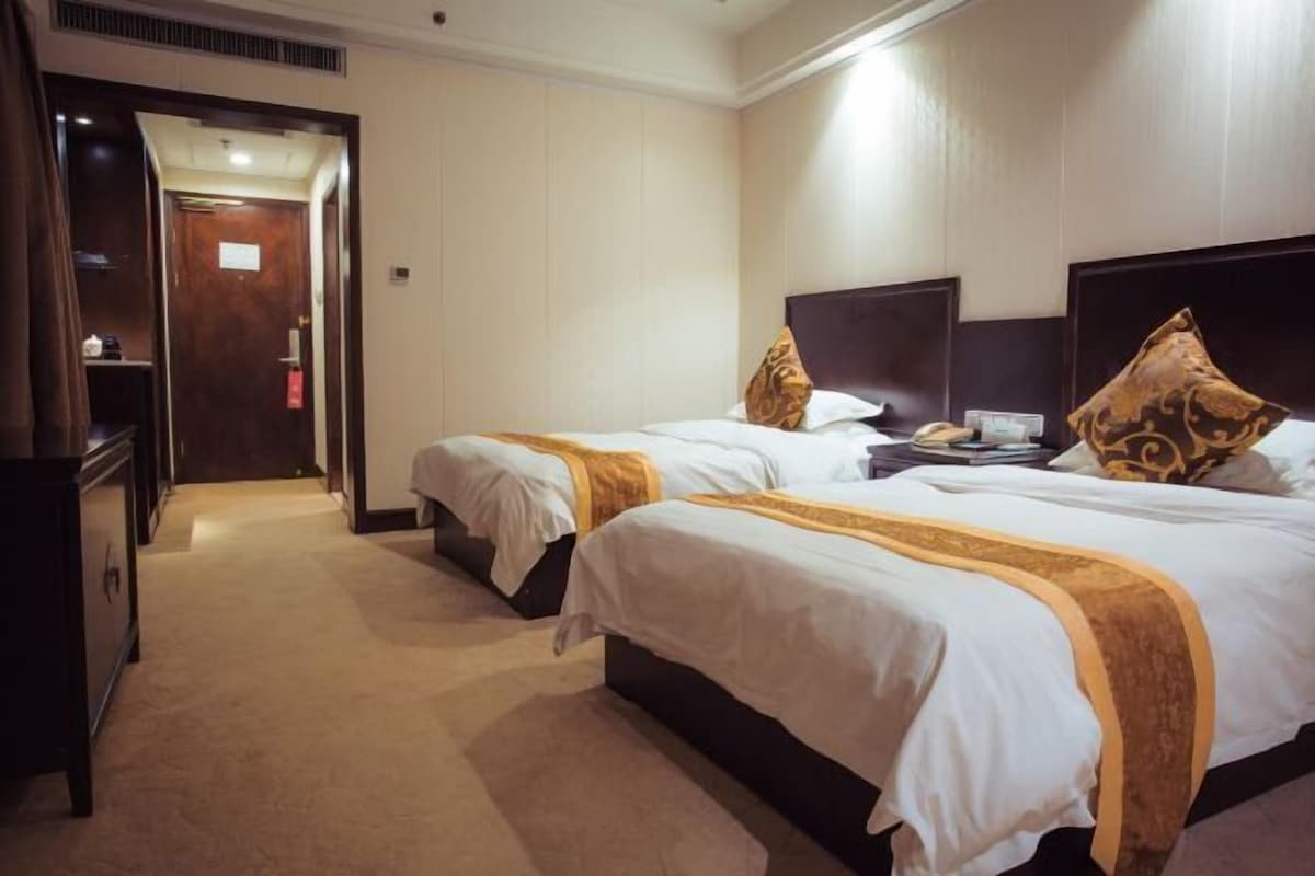 A hotel room with two beds, a desk, and a wardrobe.