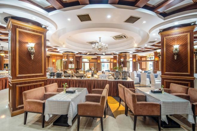 A restaurant with round tables, cushioned chairs, and a central bar area.