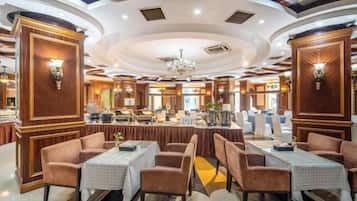 A restaurant with round tables, cushioned chairs, and a central bar area.