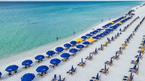 A beach with rows of blue and yellow umbrellas and sun loungers. - 2 Bedroom - Pelican Beach Resort 1201 - Gorgeous Remodeled Gulf Front corner unit! (Destin)