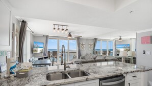 A modern kitchen with a marble countertop, double sink, and white cabinetry. - 2 Bedroom - Pelican Beach Resort 1201 - Gorgeous Remodeled Gulf Front corner unit! (Destin)