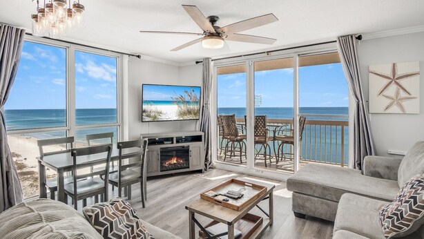 A living room with a TV, a fireplace, and a view of the beach. - 2 Bedroom - Pelican Beach Resort 1201 - Gorgeous Remodeled Gulf Front corner unit! (Destin)
