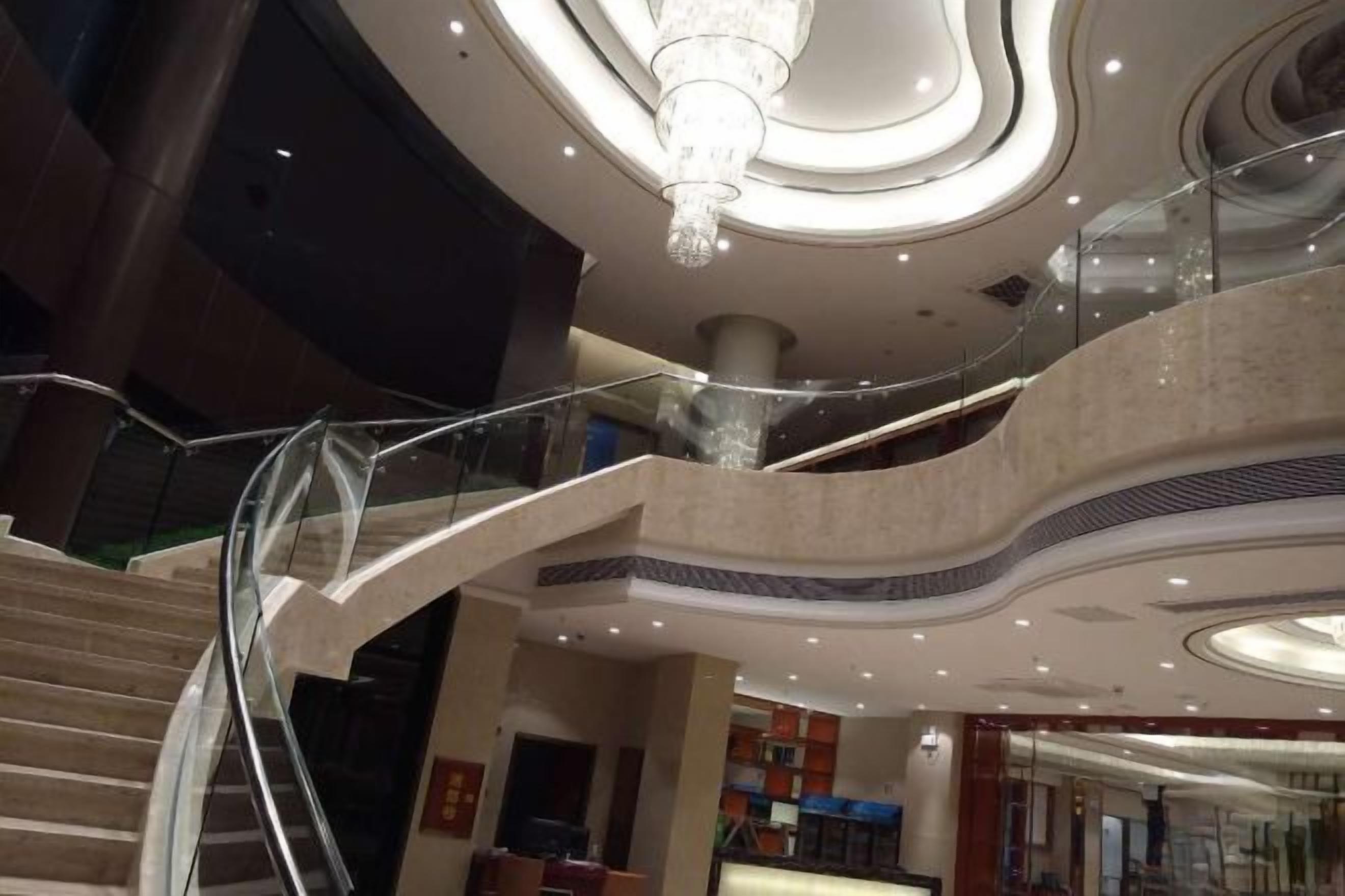 Een meerlaags interieur met een glazen balustrade, een kroonluchter en een modern plafondontwerp.