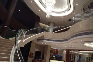 Ein mehrgeschossiges Interieur mit einer Glasgeländer-Treppe, einem Chandelier und einem modernen Deckenstil.