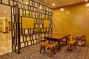 A hotel room with a wooden partition, a dining table with chairs, and a small table with a lamp. - Xiya Hotel (Foshan)