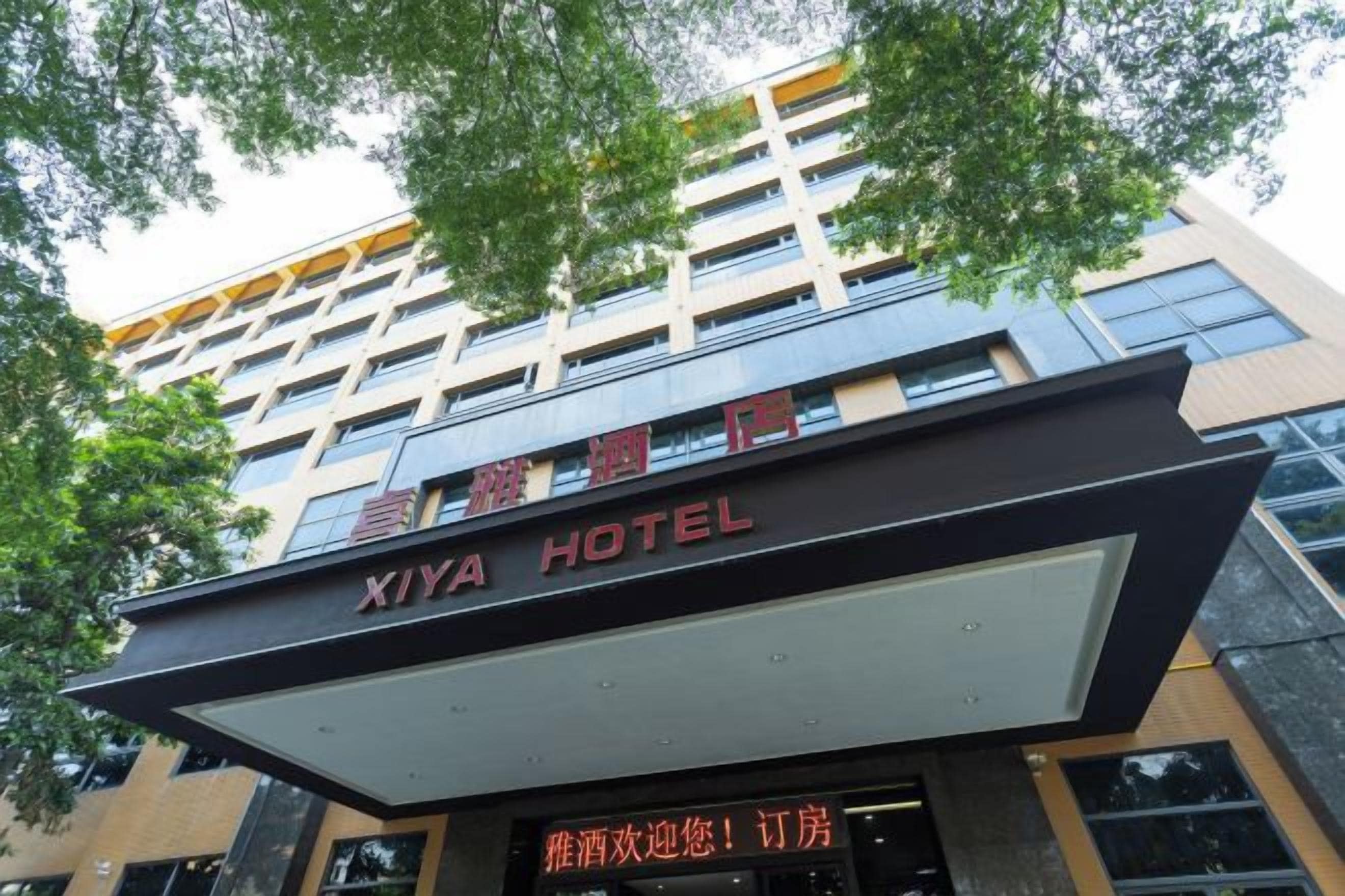 The exterior of the Xiya Hotel with a prominent sign and a modern architectural design.