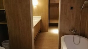 A modern bathroom with a bathtub, wooden flooring, and a built-in vanity. - Xiya Hotel (Foshan)