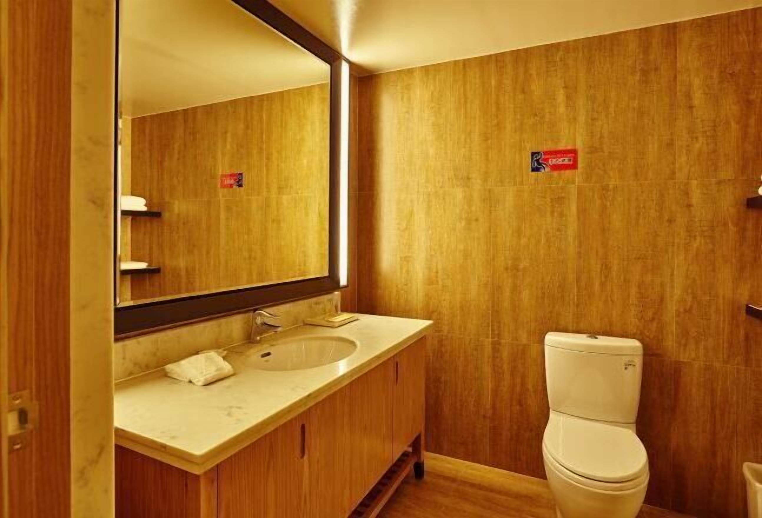 A bathroom with a wooden vanity, a sink, and a toilet.