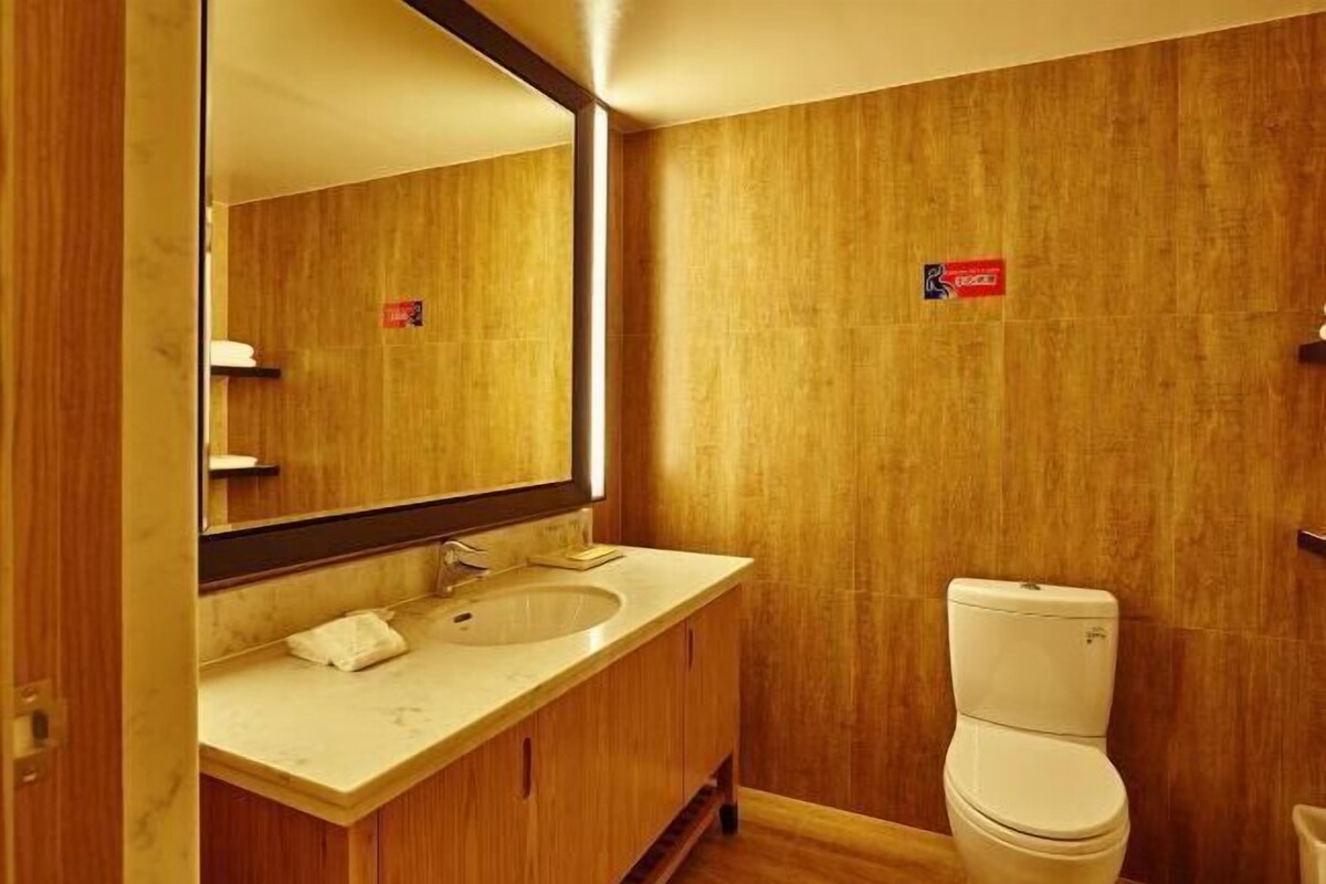 A bathroom with a wooden vanity, a sink, and a toilet.
