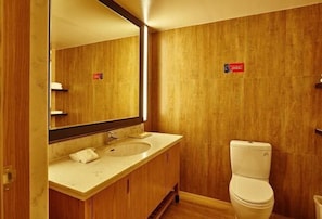 A bathroom with a wooden vanity, a sink, and a toilet. - Xiya Hotel (Foshan)