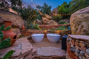 A garden with large rocks, a cactus, and a stone wall.