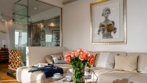 Ein modernes Wohnzimmer mit einem Glastisch, einer Couch und einem gerahmten Kunstwerk an der Wand.