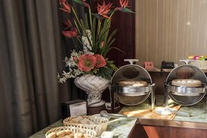 A buffet setup with food containers, a vase with flowers, and a sign indicating the buffet area. - Haiyue Junlan Hotel (Huangshan City)