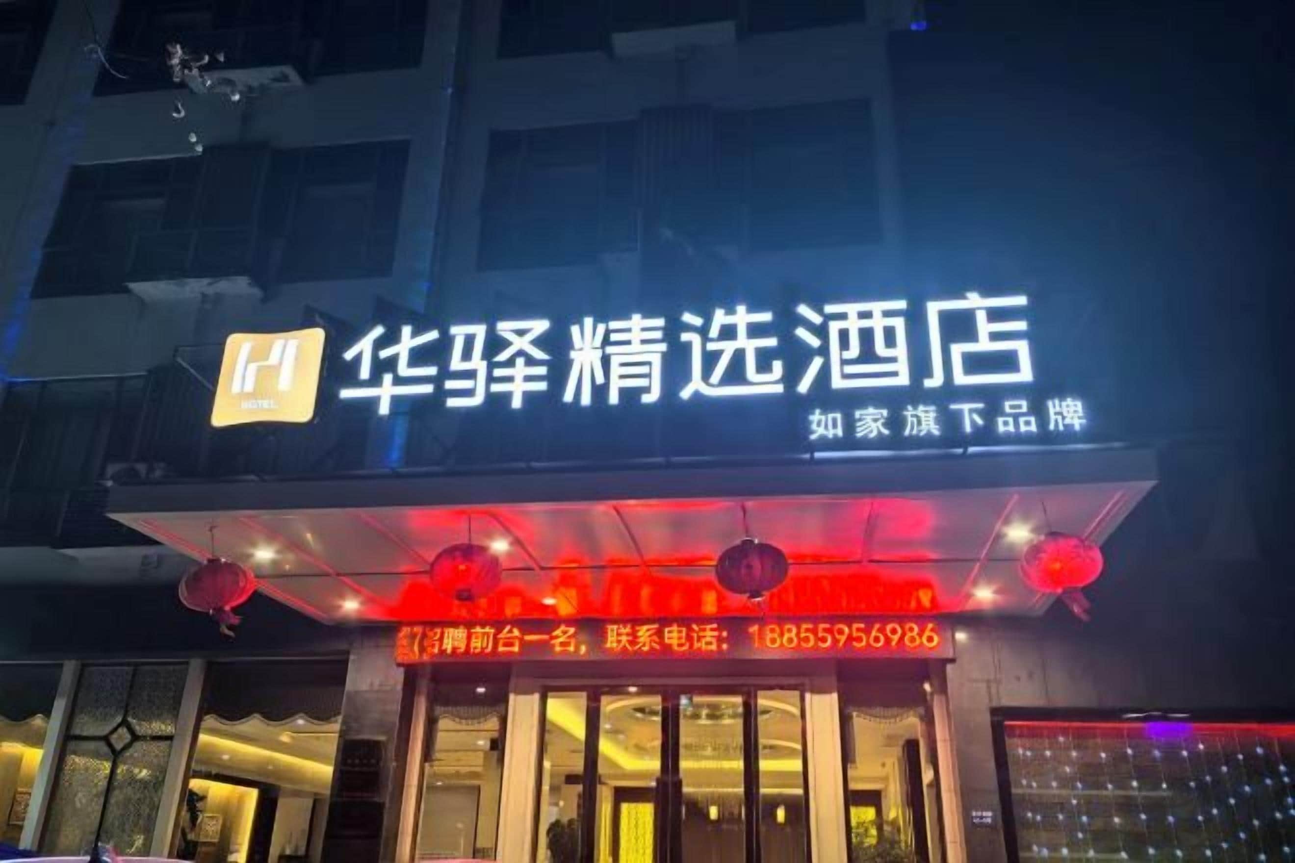 A hotel sign with illuminated text and a contact number.