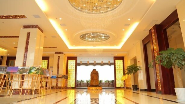 A spacious lobby with a central statue, a chandelier, and a reception desk with framed artwork. - Haiyue Junlan Hotel (Huangshan City)