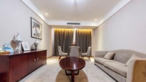 A modern hotel room with a round wooden coffee table, a sofa, a dining table with chairs, and a cabinet. - Haiyue Junlan Hotel (Huangshan City)