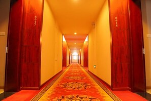 A hotel hallway with a red carpet, wooden doors, and a patterned carpet runner. - Haiyue Junlan Hotel (Huangshan City)