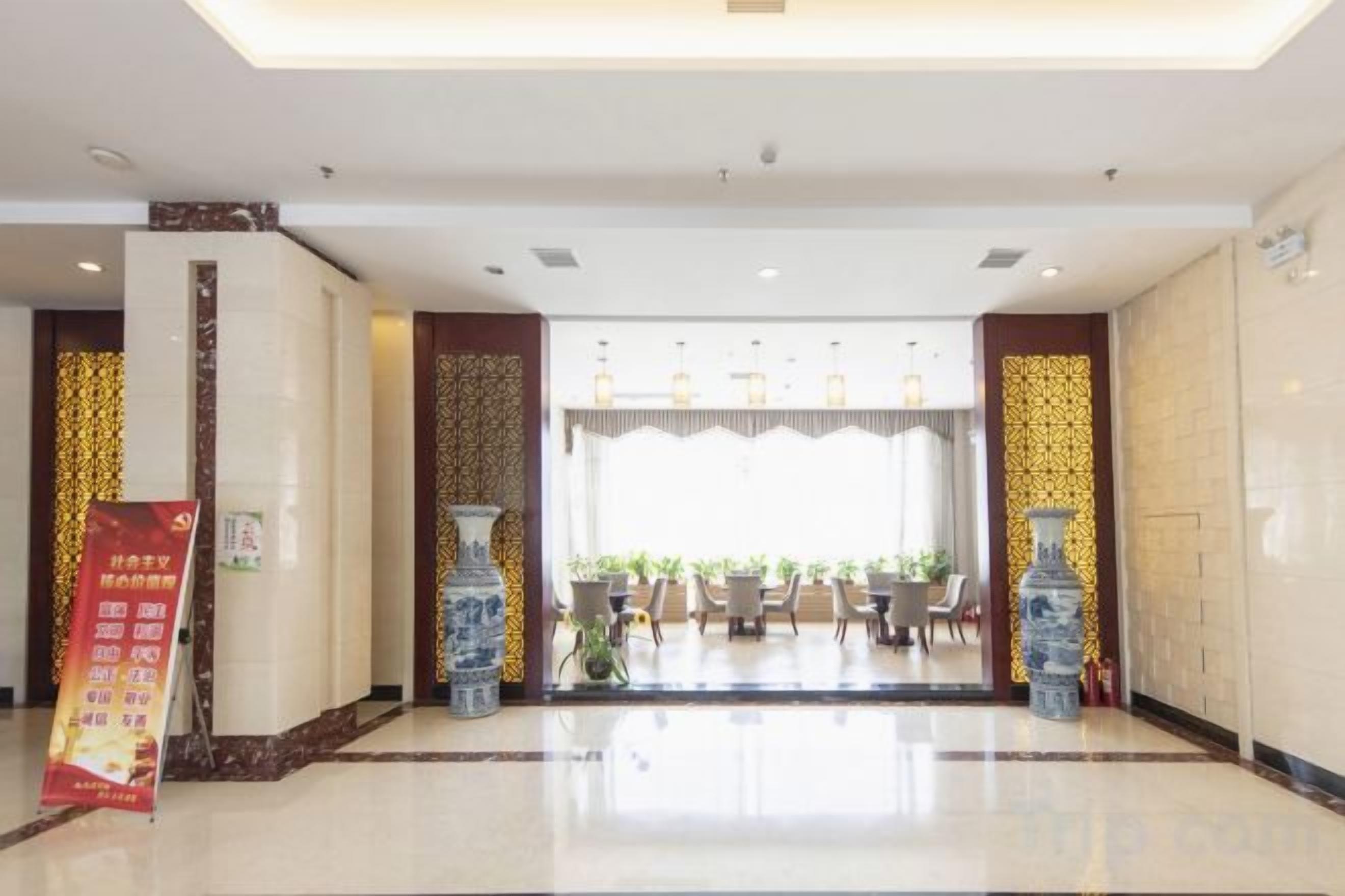 A hotel lobby with a reception desk, seating area, and decorative vases.