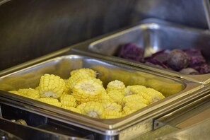 Un buffet con una sezione dedicata al mais e un'altra ai vegetali viola.