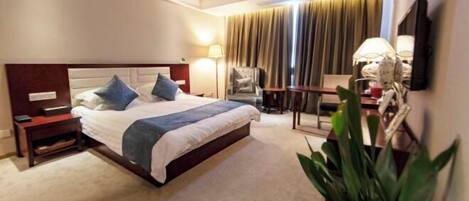 A hotel room with a bed, bedside tables, a lamp, a chair, a TV, and a plant.